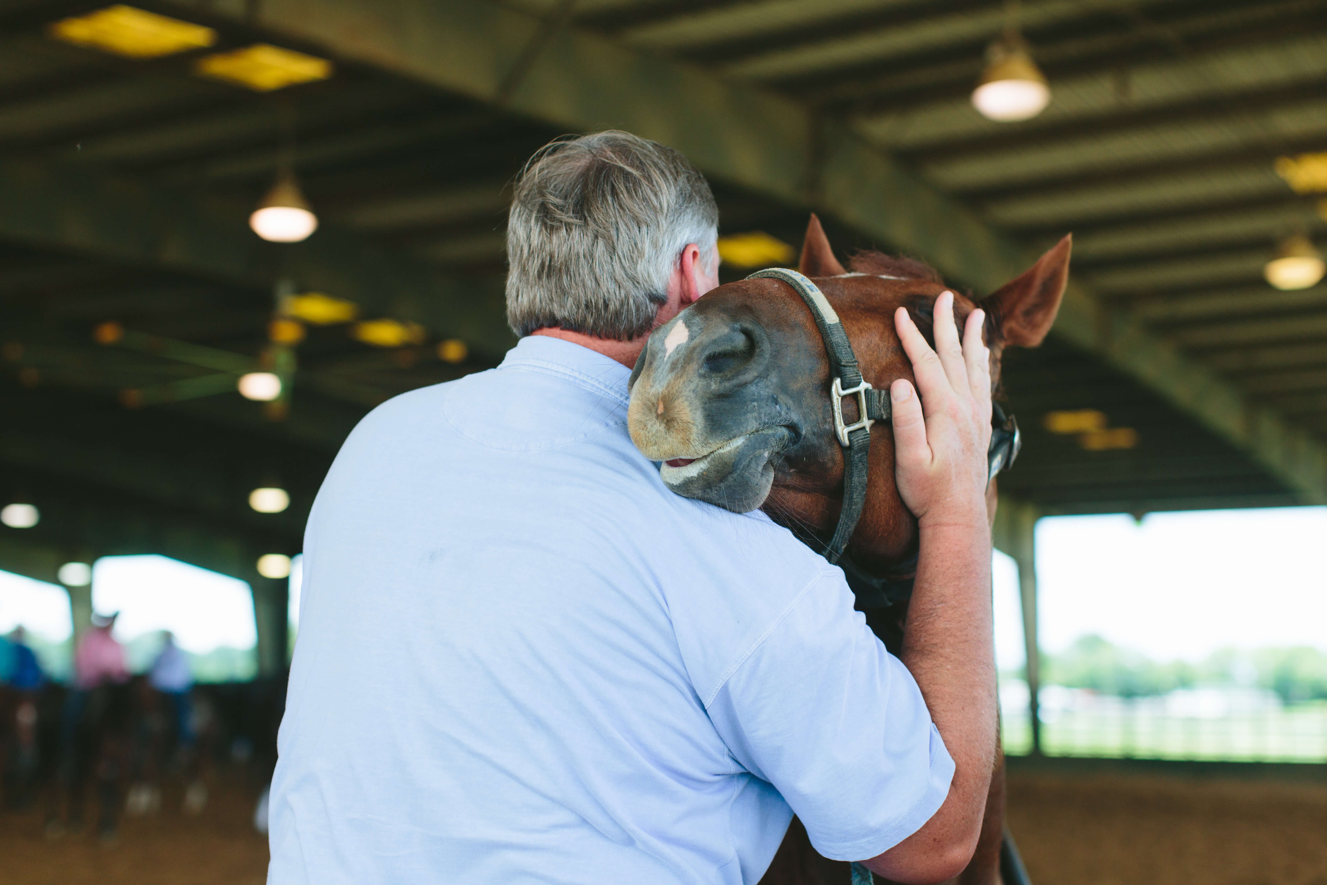 man hugging horse