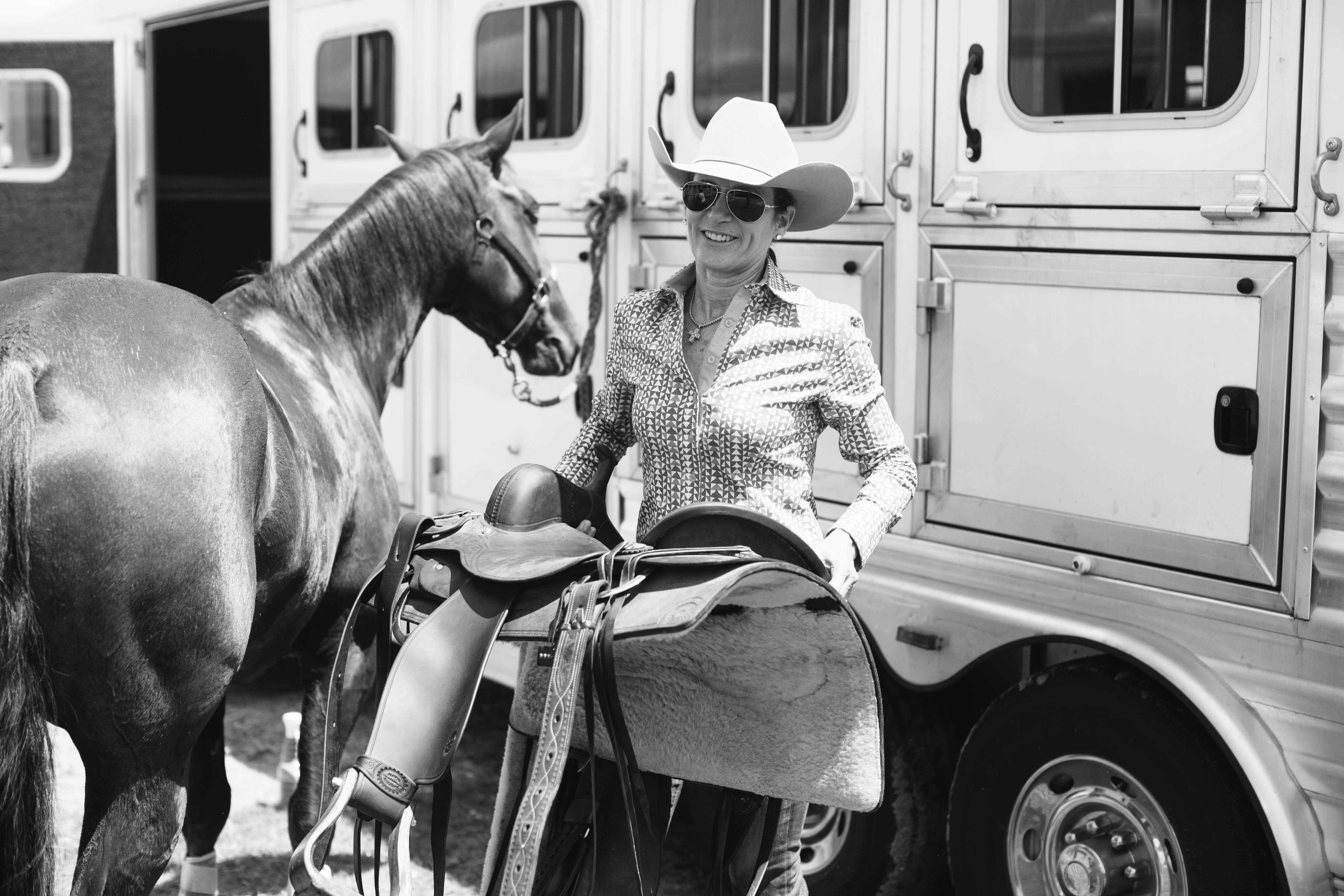 cowgirl taking saddle off horse