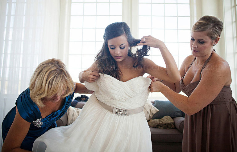 a bride getting into her reem acra gown for her hampstead wedding in alabama
