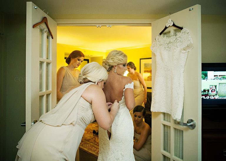 an auburn bride putting on her legends by romona keveza wedding gown