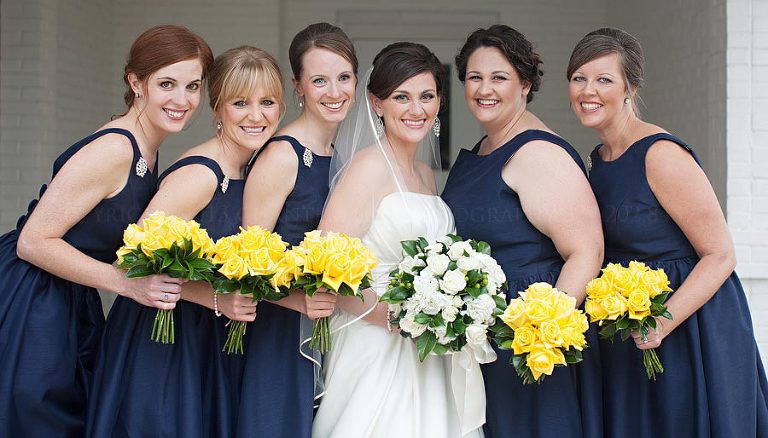 bridesmaids in navy dresses with yellow bouquets