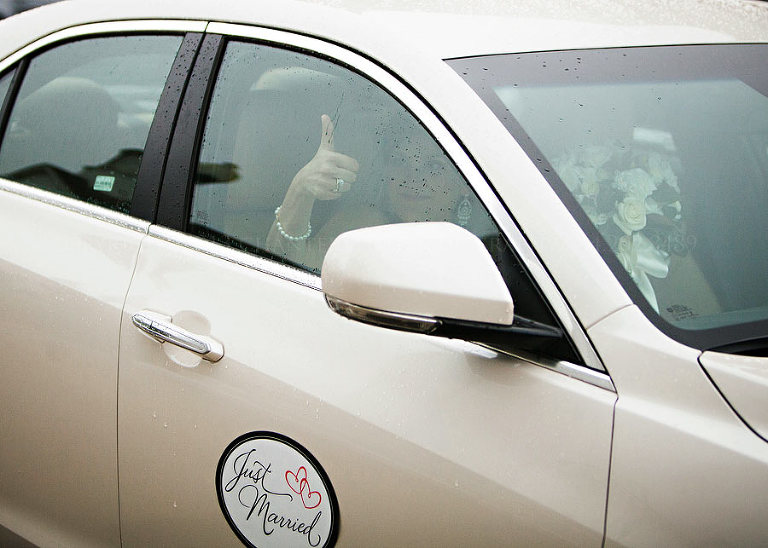 bride gives thumbs up as they leave in a cadillac
