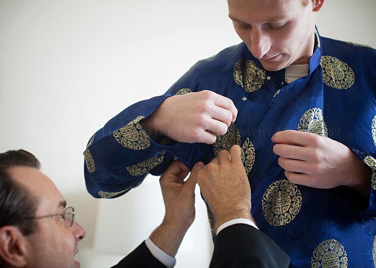 groom putting on traditional vietnamese wedding outfit