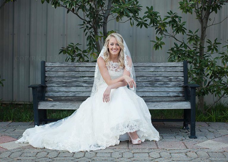 bride in lace wedding dress sitting on a bench