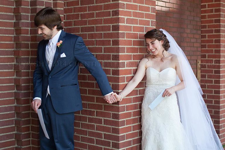 bride and groom hold hands around a corner