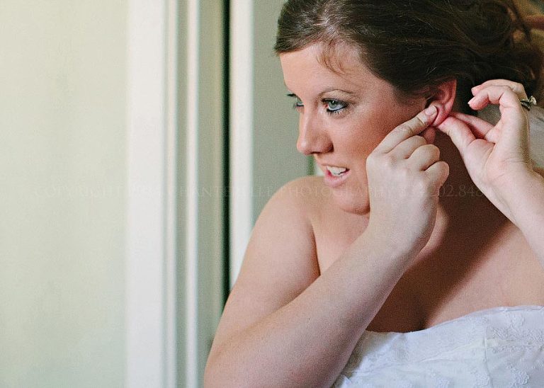 bride putting on earrings before destin wedding