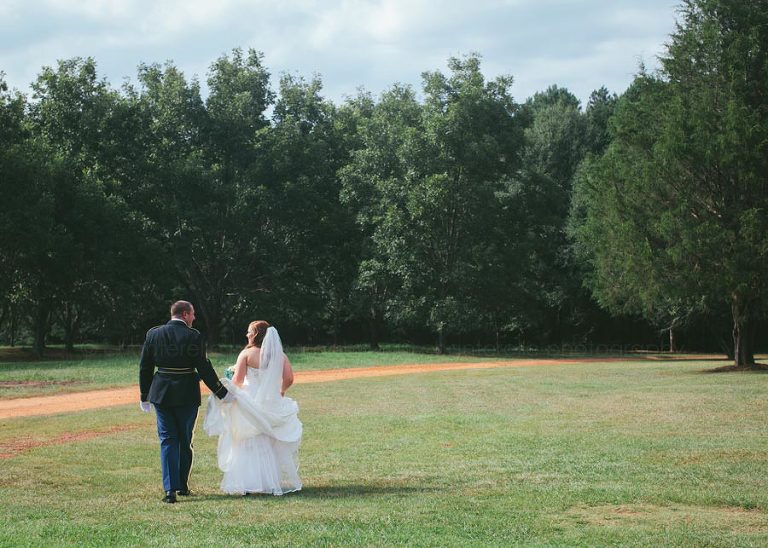 bride and groom walking through field in alabama