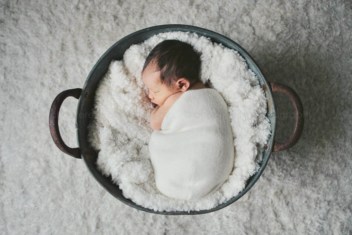 newborn baby swaddled in bucket
