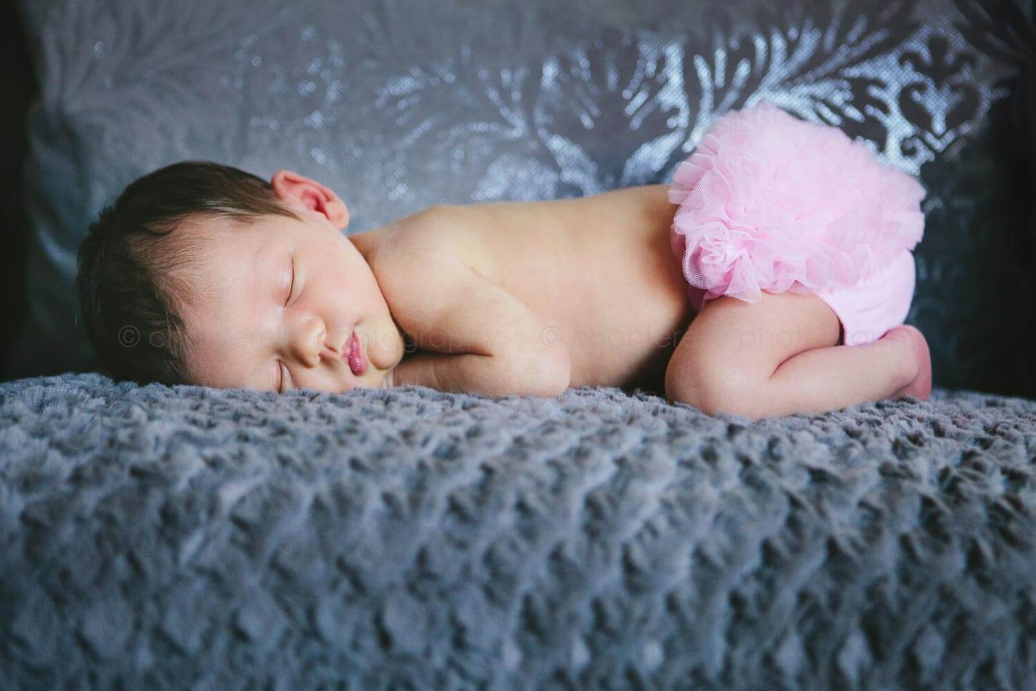 newborn baby girl with pink ruffled bloomers