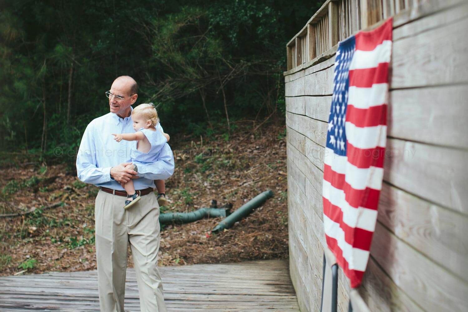 grandpa carrying grandson with american flag in background