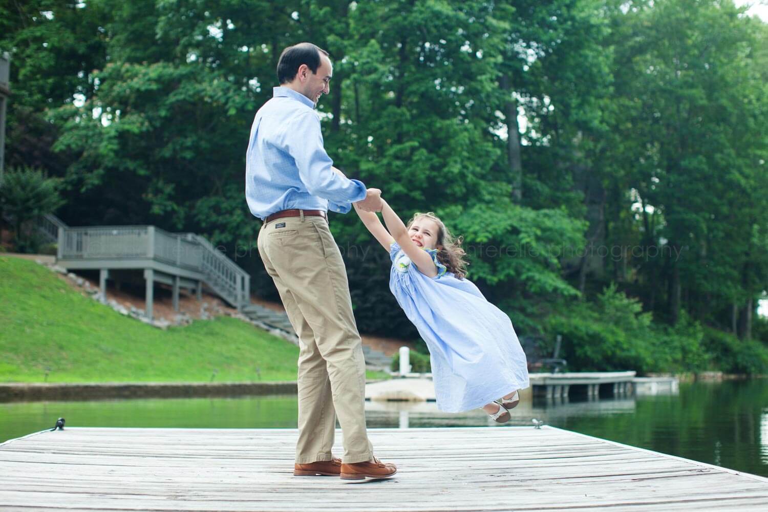 dad swinging daughter around on dock at lake martin