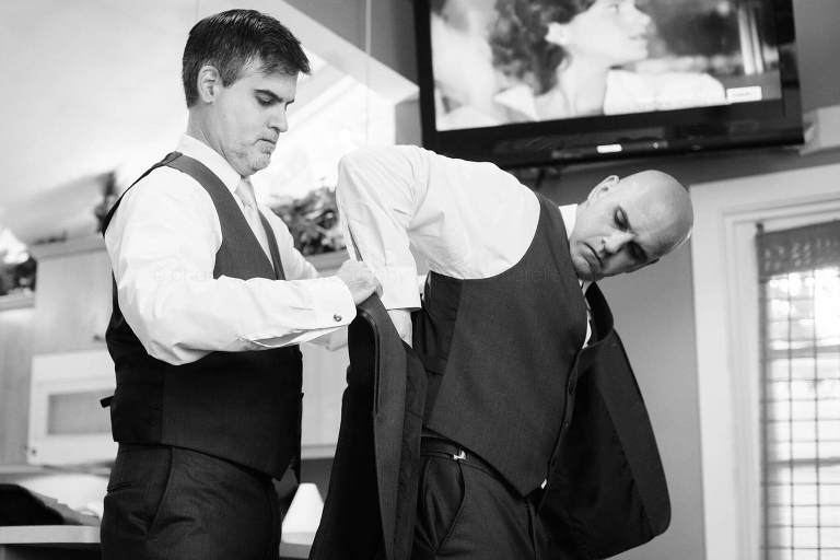 best man helping groom put on his jacket before florida wedding