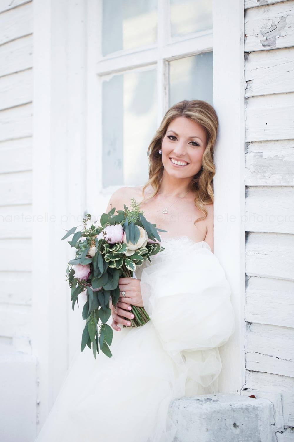 bride against white weathered beach house