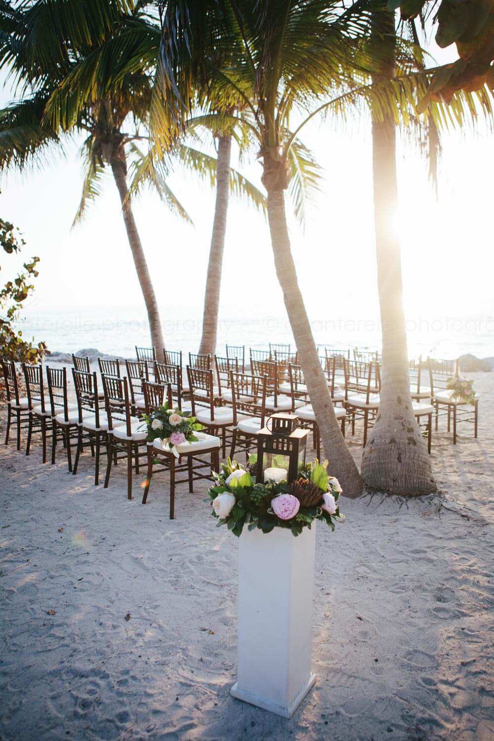 chairs and flower lanterns set up for fort zachary taylor beach wedding ceremony