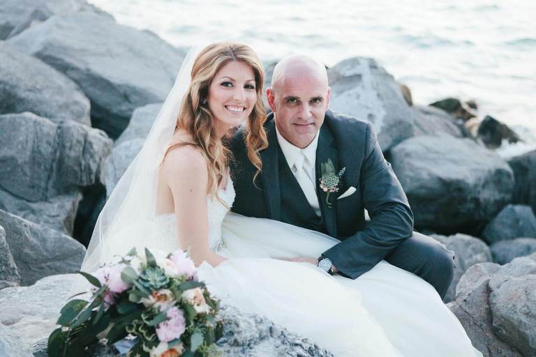 bride and groom sitting on rocks jetty at fort zachary taylor beach wedding