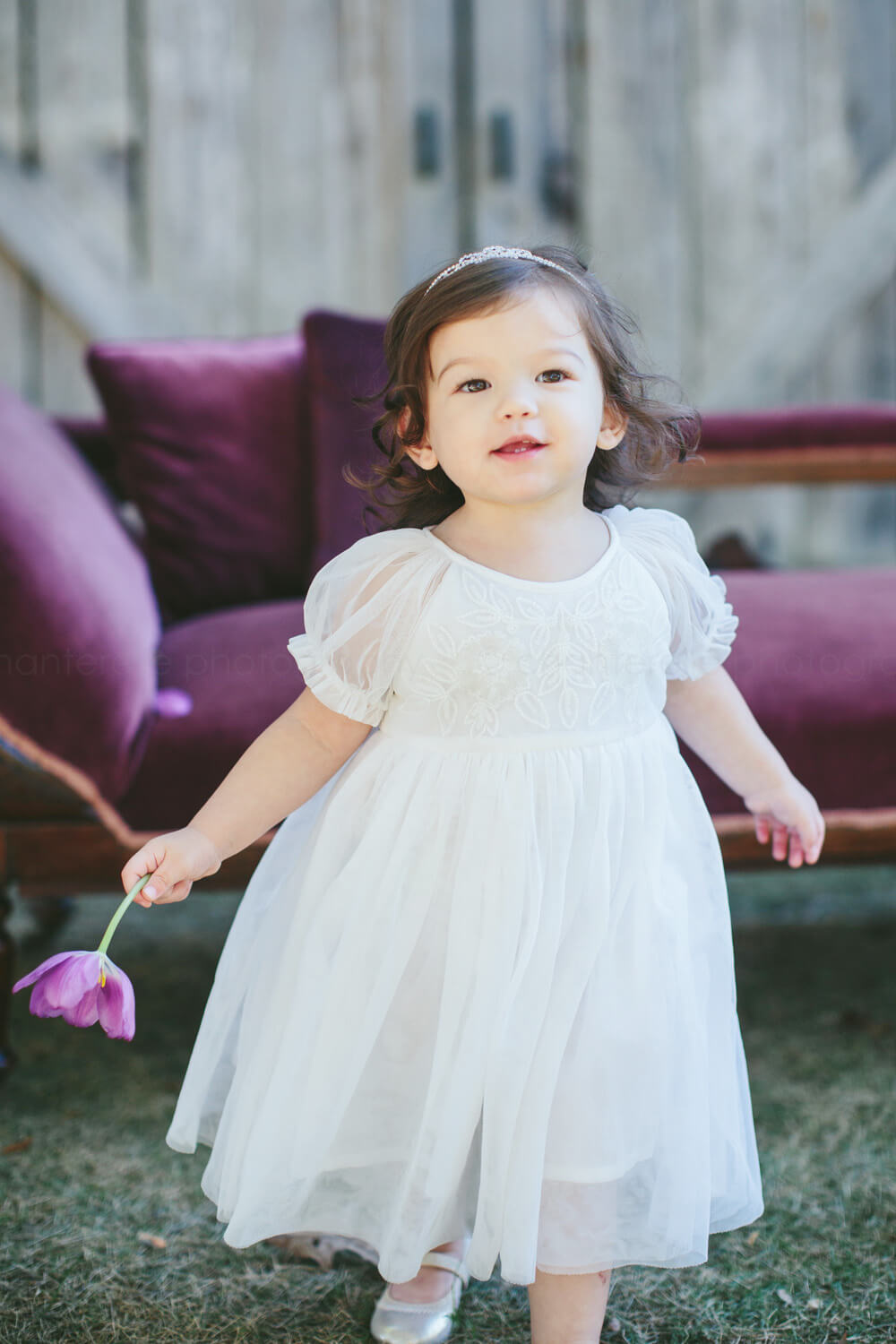 baby girl in white dress with purple chaise