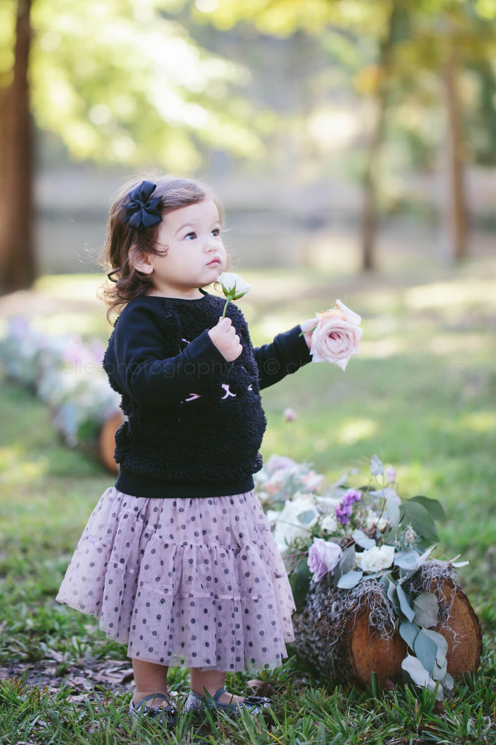 baby in polka dot skirt carrying flowers