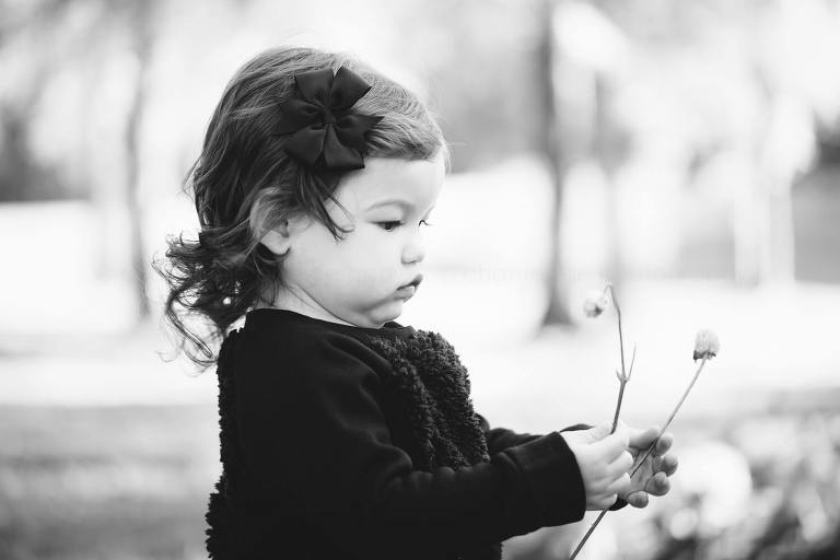 black and white portrait of baby picking flowers