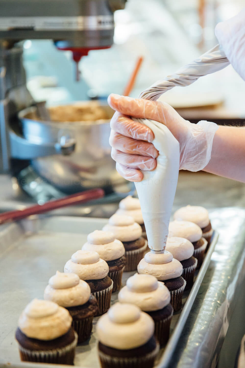 piping icing on cupcakes at cake flour bakery in louisville