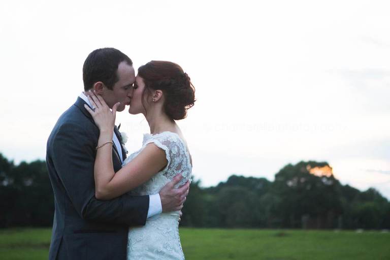 bride and groom kissing as sun sets