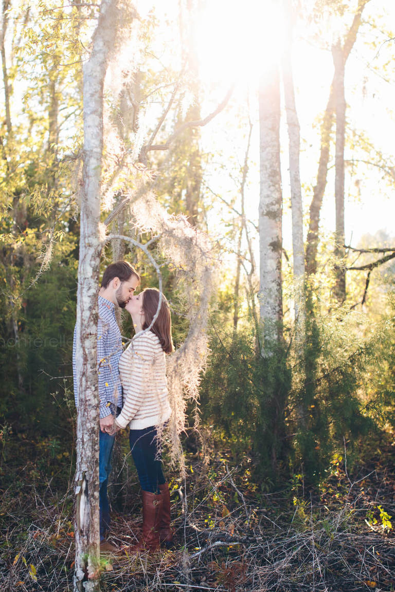 engaged couple kissing behind backlit tree in alabama 
