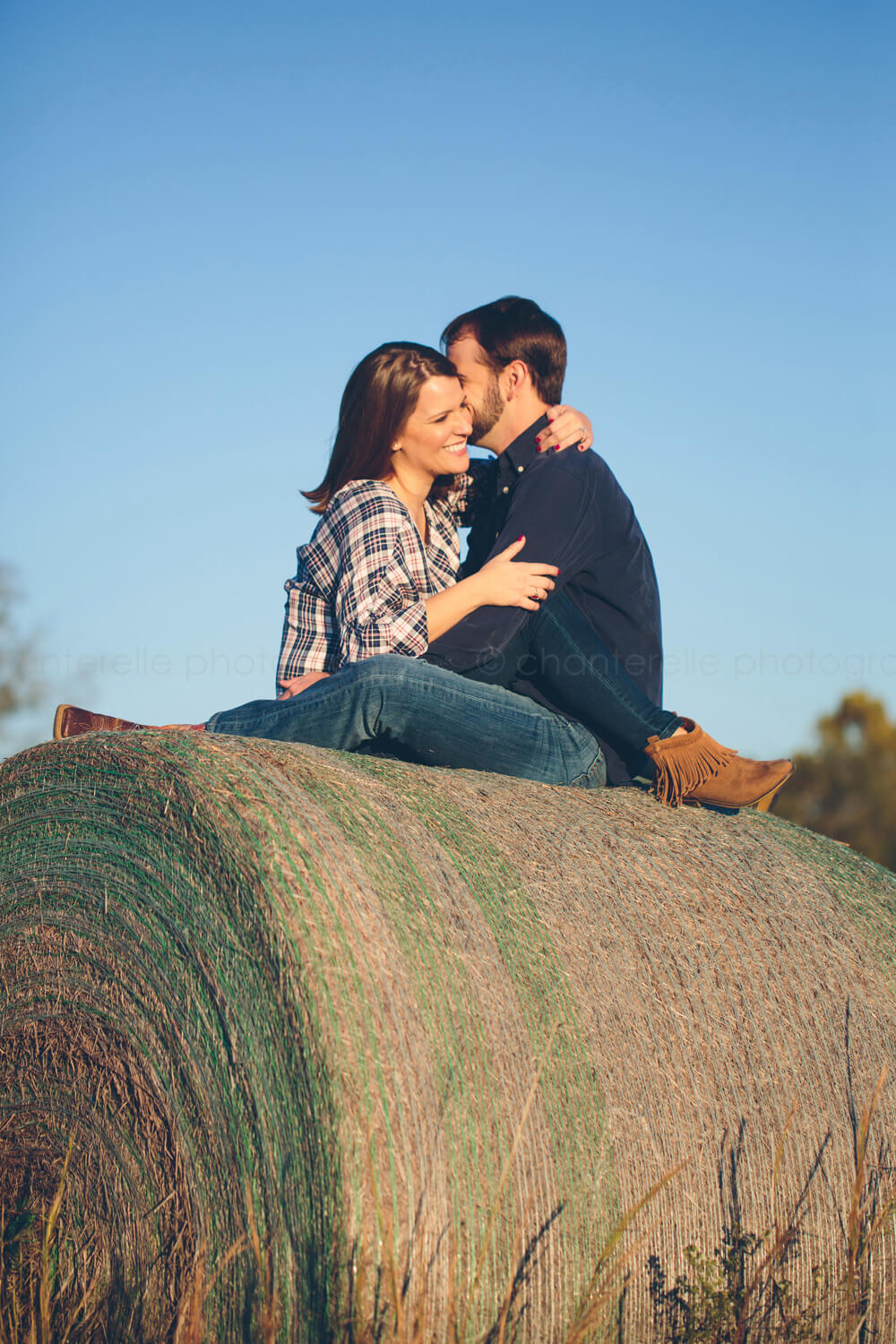 couple snuggling on top of haybale during farm engagement session