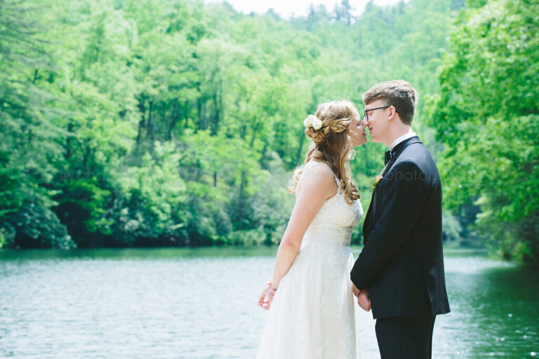 bride and groom almost kissing next to lake at lonesome valley
