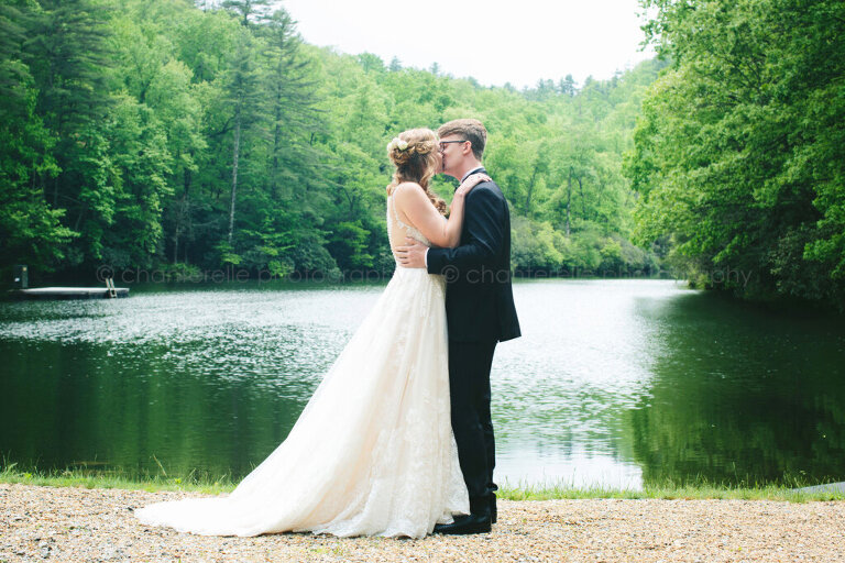 bride and groom kiss next to lake at lonesome valley