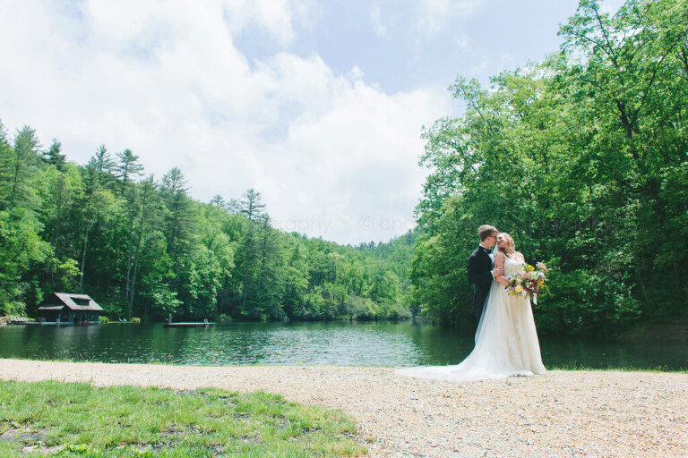 bride and groom snuggling next to north carolina lake