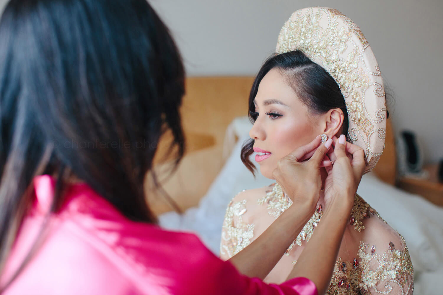 bridesmaid putting on bride's earrings