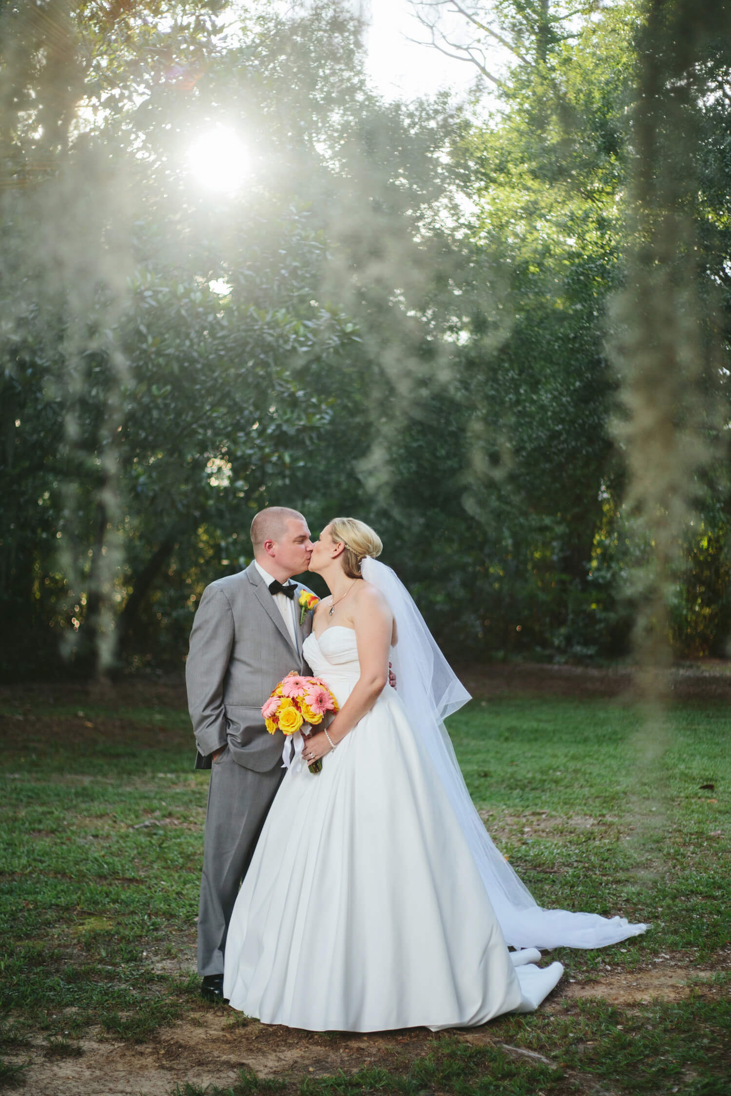bride and groom kiss under spanish moss at the elms
