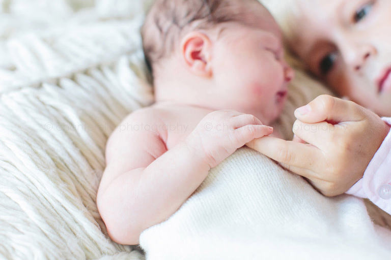 newborn holding big brothers finger