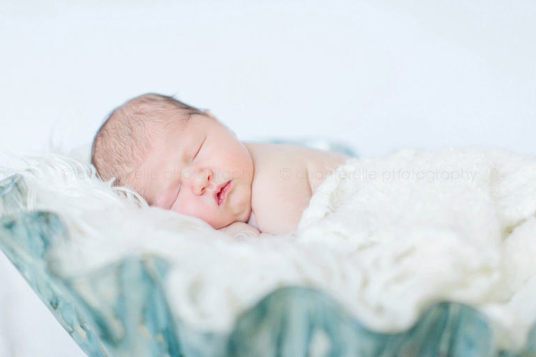 newborn baby sleeping in fluted bowl