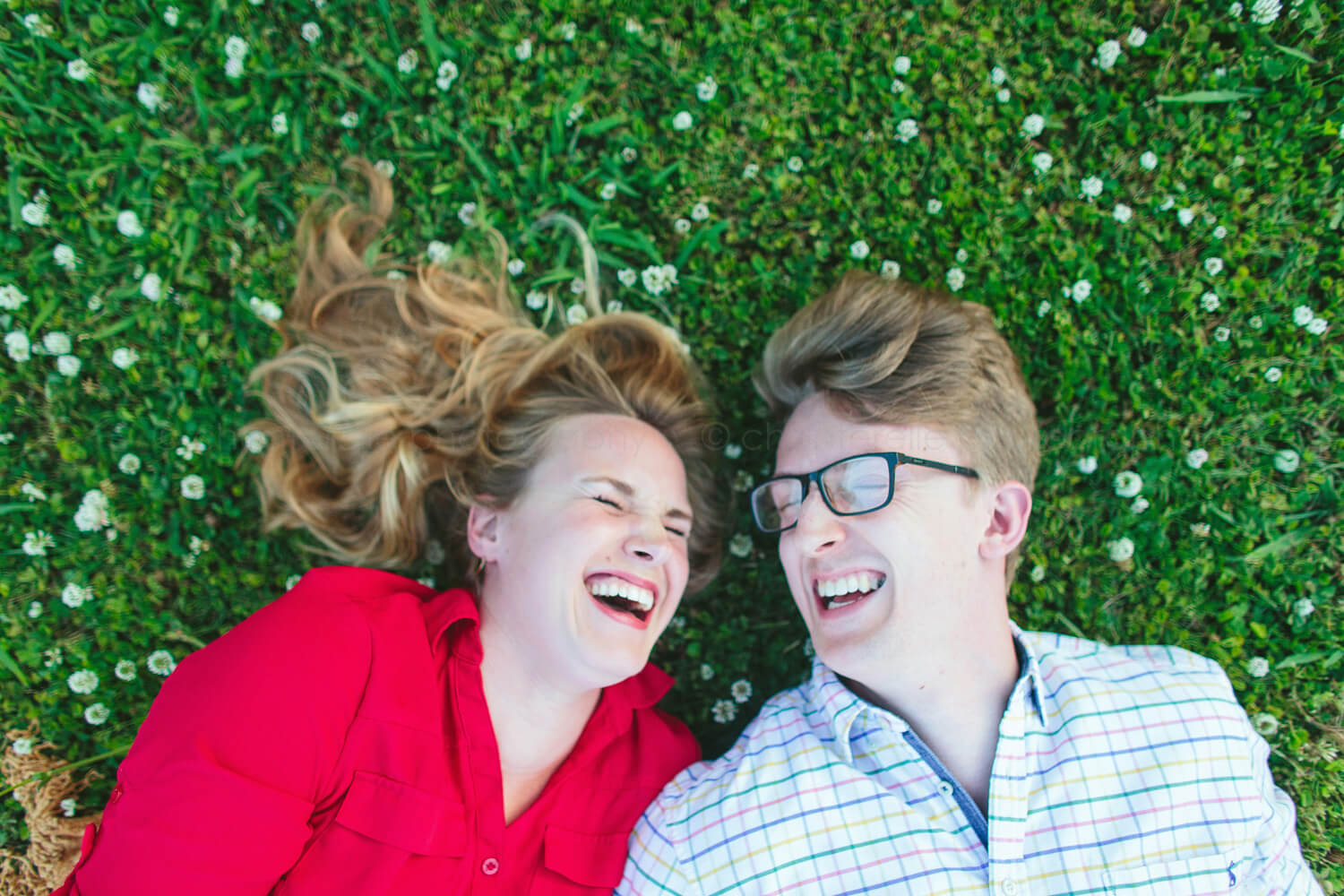 engaged couple laughing in the grass