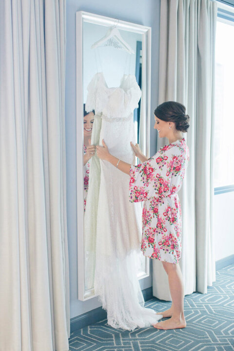 bride in floral robe looking at wedding gown