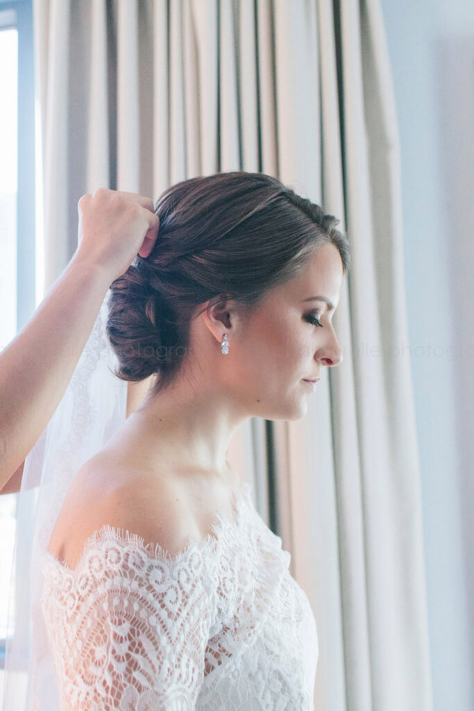 bride with eyes closed while veil is put on