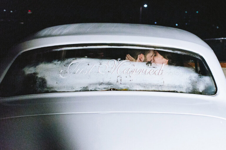 bride and groom in white bentley with just married sign