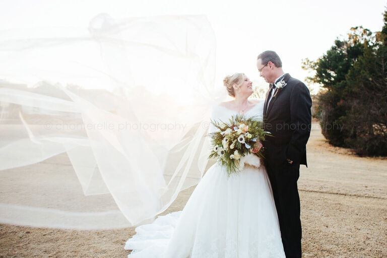 bride and groom with veil blowing in the wind