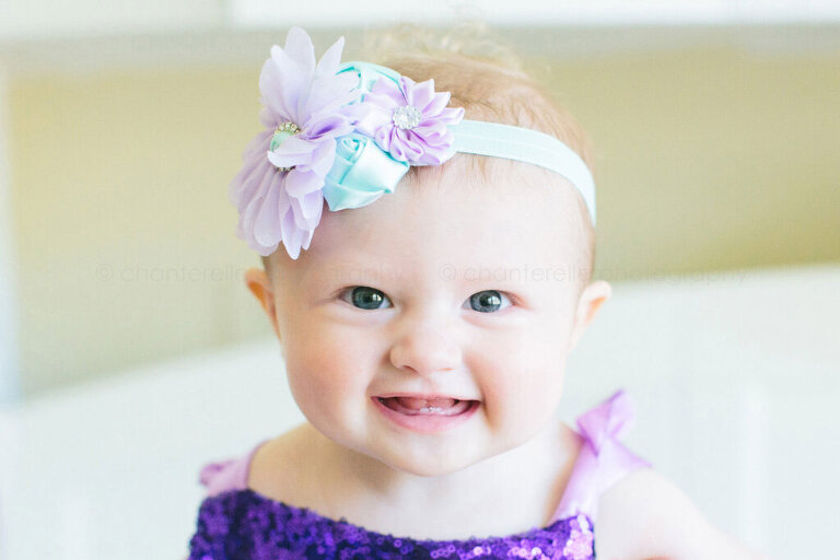 smiling baby wearing floral headband and purple sequins