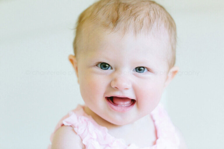 blue eyed baby girl looking at camera and smiling