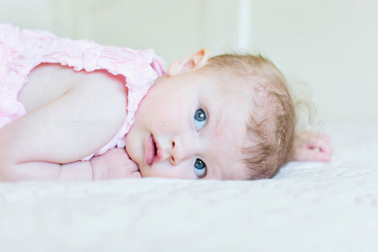6 month old baby girl lying on white bed