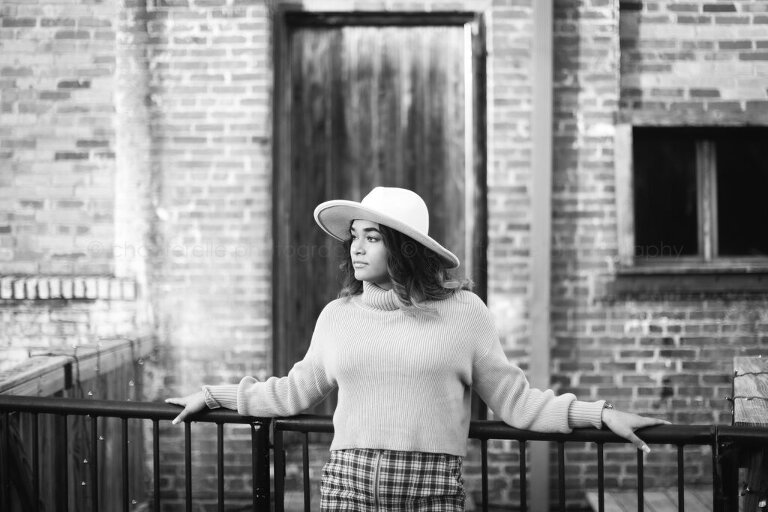 black and white portrait of pretty brunette woman in a light hat and plaid skirt